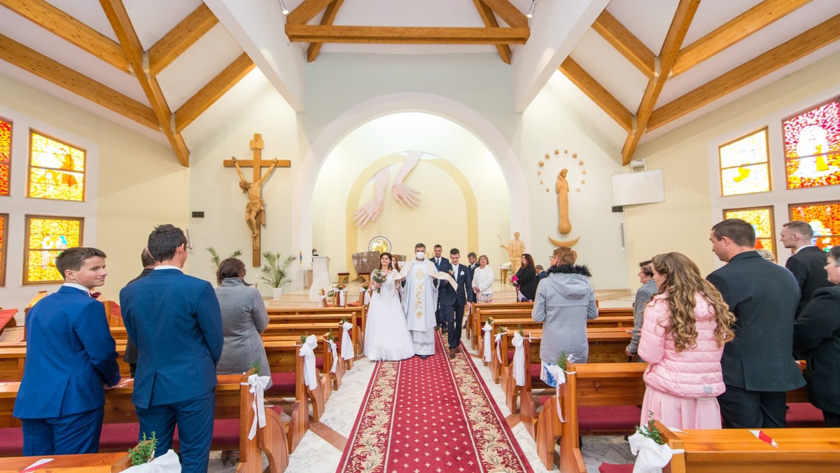 A bride and groom walk down the aisle after their wedding ceremony in a colorful church.